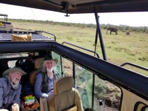 Mick and Ann in Kenya, with a mama elephant and her baby in the background